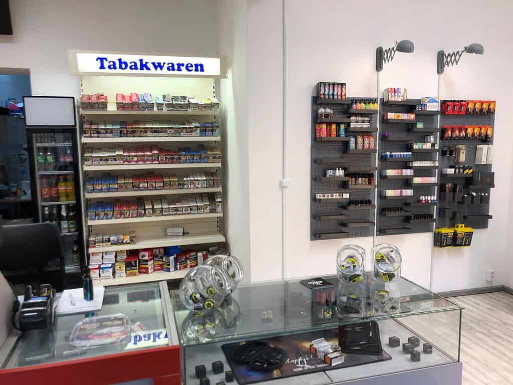 Ausschnitt eines Tabakwaren-Displays in einem Handelsgeschäft mit Regalen voller Zigaretten, Tabakprodukte und Zubehör, inklusive Warenvorschau und Verkaufsfläche.