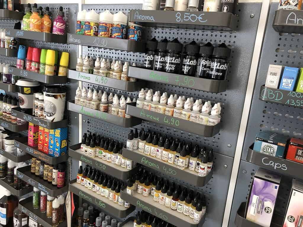 Aromen in Fläschchen auf einer Verkaufsregalwand, verschiedene Sorten und Preise, für E-Zigaretten und Liquids.