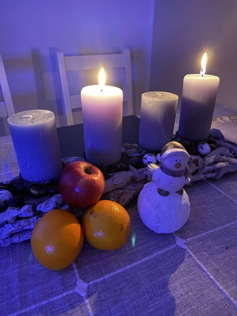 LETZ Go zu Weihnachten 16 Stumpenkerzen in weiß und grau, festlich dekoriert mit Weihnachtsdeko und Früchten, schafft eine gemütliche, winterliche Atmosphäre. Perfekt für festliche Tischdeko und Weihnachtsstimmung.